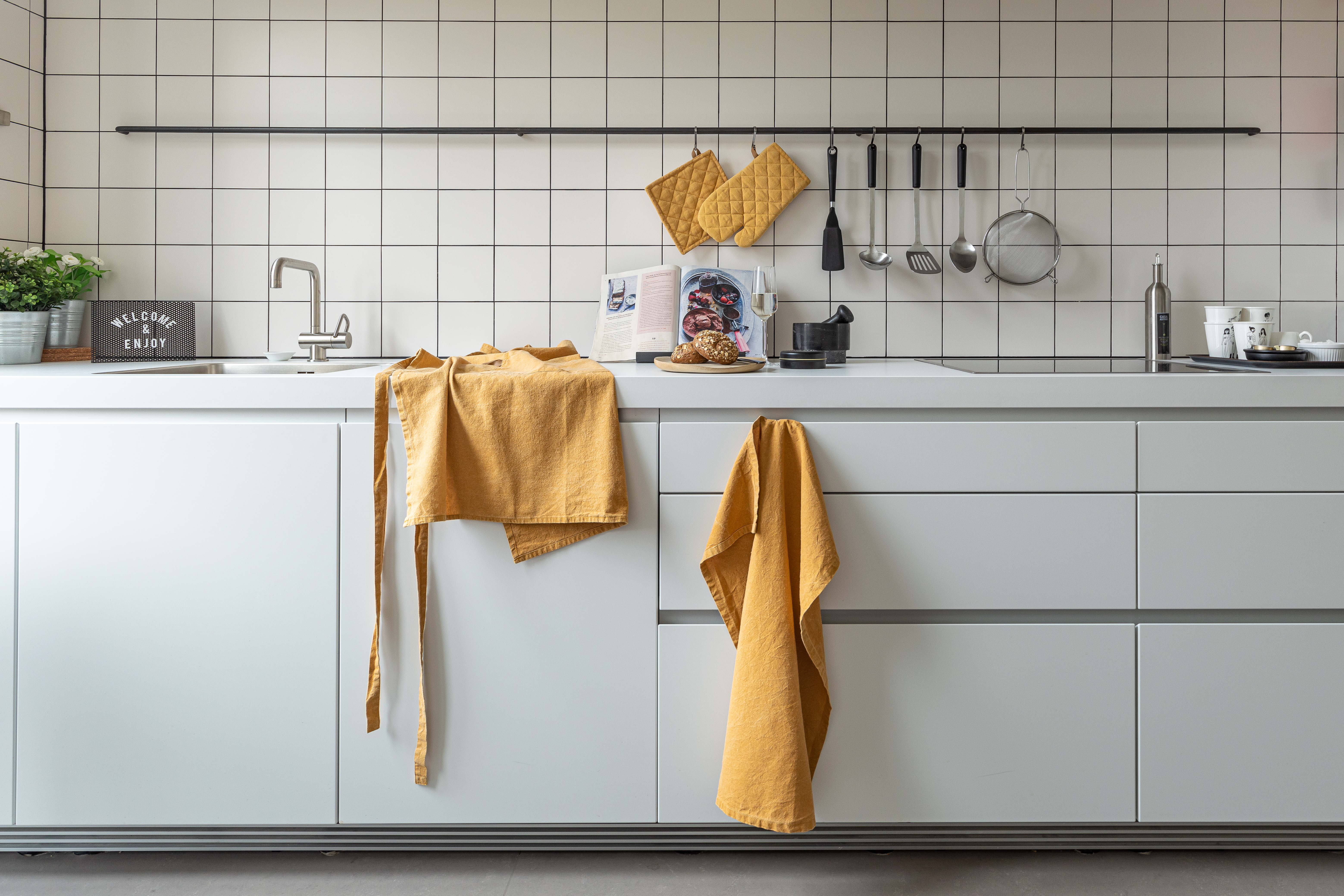 Kitchen apron, pot holder, oven mitt and kitchen towel in kitchen.