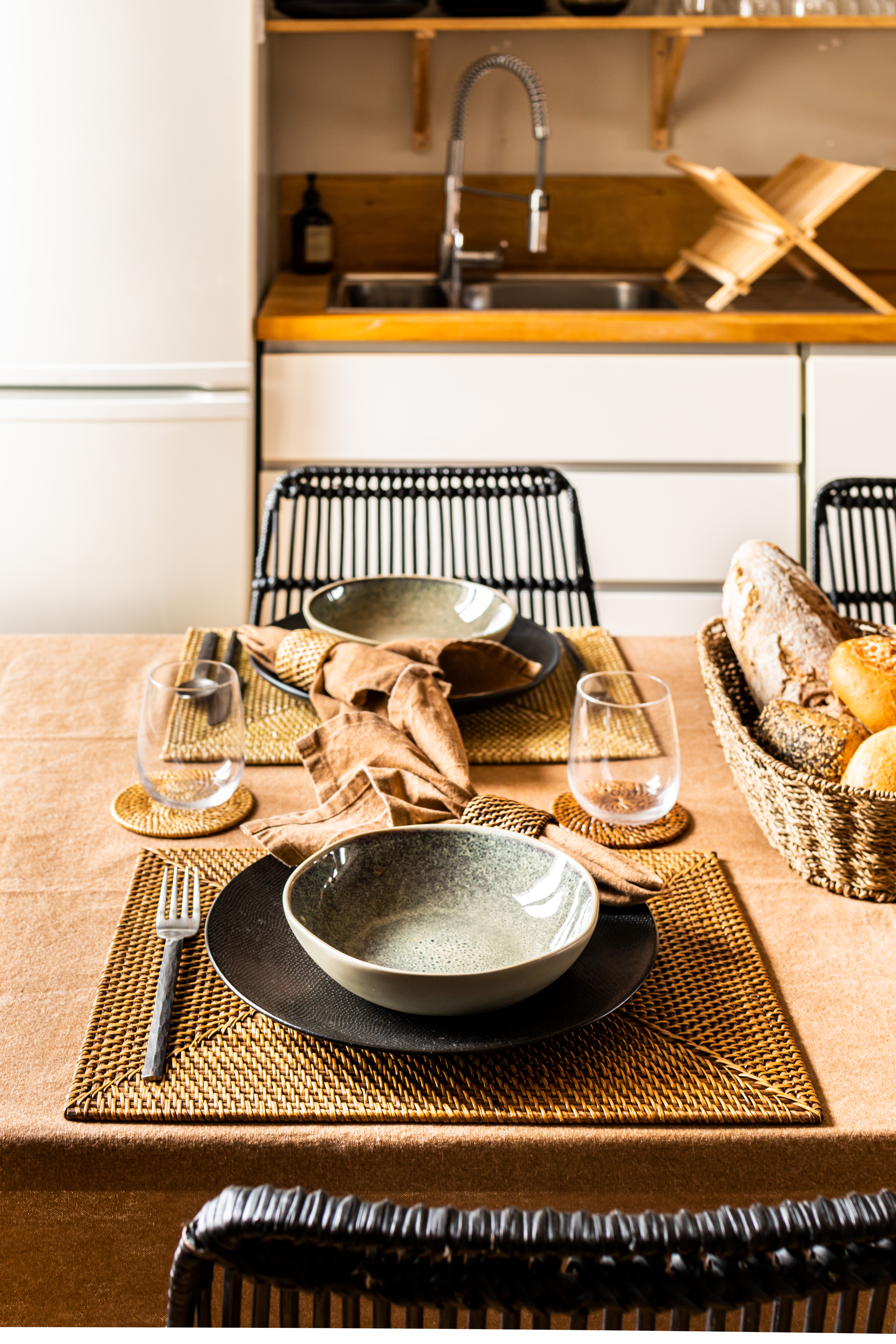 Een gedekte tafel met rechthoekige placemats, glasonderzetters en servet met servetring in Rattan materiaal